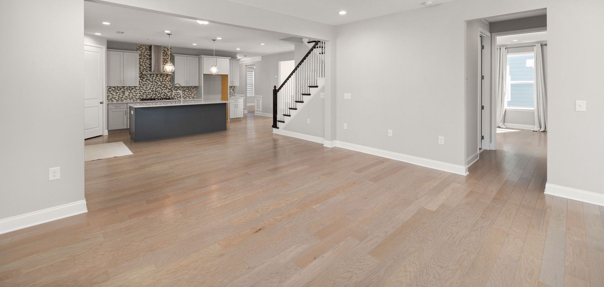 Spacious open-concept living room with hardwood floors and modern kitchen design.