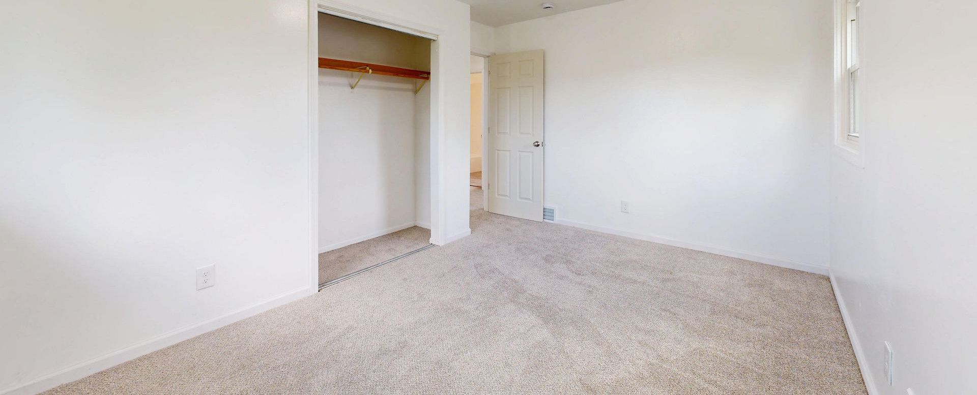 Spacious, empty room with plush carpet and open closet, well-lit
